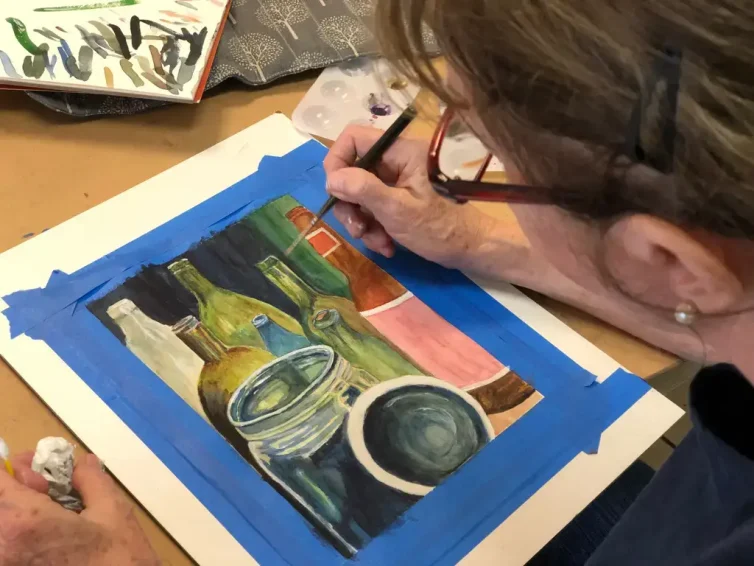 Adult student painting detailed bottles and jars with reflections during Art Class in Round Rock