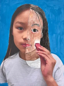 Young artist drawing half of their face over a self-photo using pastel during Art Class in South Austin, blending abstract and personal expression