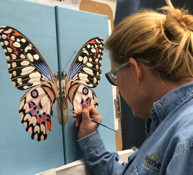 Adult painting a beautifully patterned butterfly during Art Class in Liberty Hill, showcasing precision and artistic growth