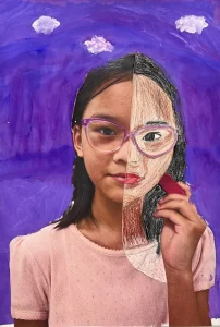 Young artist drawing half of their face over a self-photo using pastel during Art Class in South Austin, blending abstract and personal expression