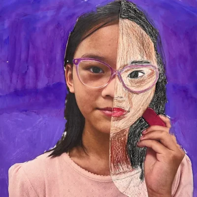 Young artist drawing half of their face over a self-photo using pastel during Art Class in South Austin, blending abstract and personal expression