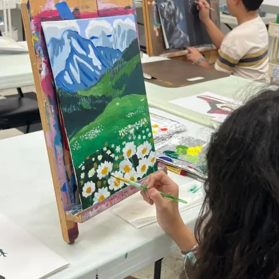 Young girl painting a mountain range with sunflowers and grassland during Art Class in Brushy Creek, showing strong landscape skills